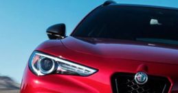 Sleek red SUV with aggressive styling, showcasing performance and luxury on a winding racetrack under blue skies.