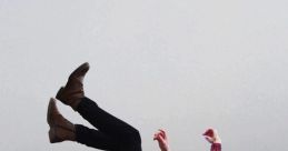 Young man in a flannel shirt appears to be falling against a muted gray background, capturing a moment of free fall.