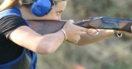 A woman wearing protective gear aims a shotgun on a shooting range, showcasing focus and skill in her stance.