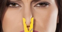 Woman making a funny face with a yellow clothespin on her nose, humorously reacting to unpleasant smells.