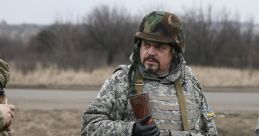 Ukrainian soldiers in camouflage uniforms discussing tactics while holding rifles in a military training environment.