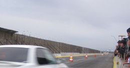 White car speeding down a racetrack, leaving tire smoke, with spectators watching from the side. Excitement in the air.