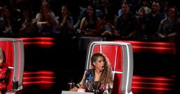 Judge excitedly reacts while sitting in the iconic chair during a live performance on "The Voice." Audience enjoys the show.