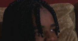 O Dog from Menace II Society smiles while gaming, showcasing his iconic braids and youthful energy in a pivotal scene.