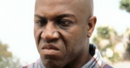 Deebo from Friday displaying an intimidating expression in a plaid shirt, embodying his tough character in the film.