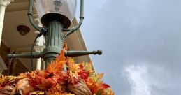 Mickey Mouse pumpkin decoration surrounded by autumn leaves at a festive Halloween celebration in front of a castle.