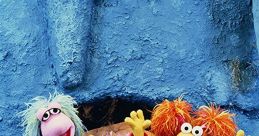 Colorful Fraggles from Fraggle Rock joyfully posing together against a vibrant blue backdrop, celebrating friendship and music.