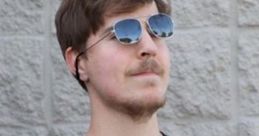 MrBeast wearing sunglasses and a black graphic T-shirt, posing confidently against a textured wall background.