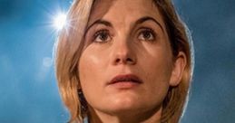 Jodie Whittaker as the Doctor in Doctor Who, gazing upwards with a thoughtful expression against a dramatic background.