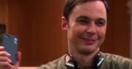 Sheldon smiling and holding his phone while wearing a Green Lantern t-shirt, showcasing his quirky personality and humor.