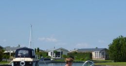 Young man steering a Sea Star 480 boat in calm waters, surrounded by scenic waterfront homes and a clear blue sky.