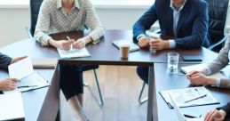 Professionals engaged in a meeting around a table with laptops, documents, and coffee, discussing important business strategies.