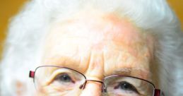 Smiling elderly woman with glasses and white curly hair, embodying warmth and love associated with grandmothers.