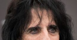 Alice Cooper speaking at a press event, showcasing his signature rock star charisma and iconic long dark hair.