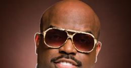 Cee Lo Green smiling confidently, wearing stylish sunglasses and a white button-up shirt, showcasing his unique style.