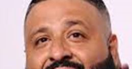 DJ Khaled smiling with a stylish haircut and beard, wearing a trendy jacket, radiating confidence and positivity.