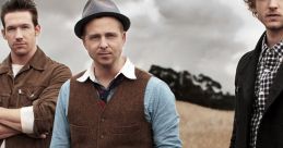 OneRepublic band members posing outdoors in a field, showcasing their unique style and artistic presence.