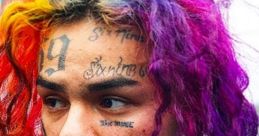 Tekashi 6ix9ine showing off vibrant, multi-colored hair and distinctive tattoos during a public appearance.