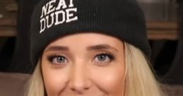 Jenna Marbles smiles while wearing a "Neat Dude" beanie, holding a phone, showcasing her fun personality.