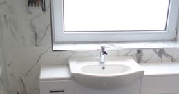 Sleek modern bathroom featuring a stylish sink, white cabinetry, and elegant marble walls, ideal for contemporary decor.