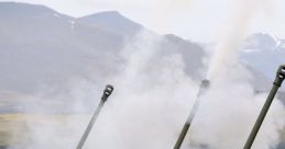 Military personnel operate artillery while smoke rises during a training exercise, showcasing gunfire and coordination.