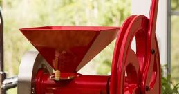 Red GrainMaker mill on a kitchen counter with flour and an elegant design, perfect for home milling grains and baking.