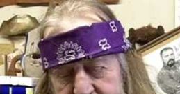 Bearded man wearing a purple bandana, head bowed in reflection, surrounded by historical artifacts.