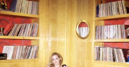 Stylish woman in a black dress relaxed on a modern couch surrounded by vinyl records, reflecting a vibrant, artistic space.