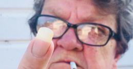 Confident older woman in glasses showing middle finger while holding a cigarette, conveying bold attitude and defiance.