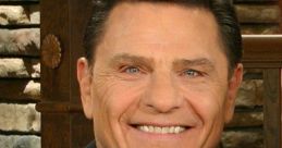 Kenneth Copeland smiles warmly, wearing a suit and tie, in front of a rustic stone backdrop, exuding charisma and positivity.