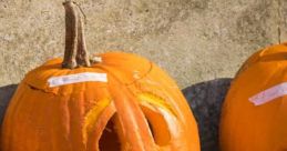 Sad-looking carved pumpkin on cobblestone, perfect for Halloween decorations and autumn festivities.