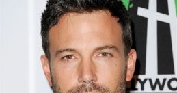 Ben Affleck in a black suit with a tie, showcasing his stylish look at a Hollywood film awards event.