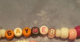 Colorful beaded bracelets spelling "GAYMER," perfect for expressing pride in gaming culture and identity.