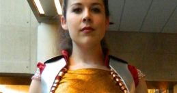 Female cosplayer in a golden and red Conlady costume with silver armor details at a comic convention.