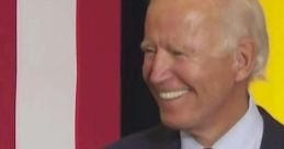 Joe Biden smiling at a podium, delivering a speech with "TODOS con BIDEN" sign, showcasing his engagement with supporters.