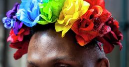 Smiling man in a vibrant rainbow flower crown, embodying pride and creativity as a gay florist celebrating diversity.