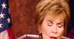 Judge Judy presiding with a serious expression, showcasing her courtroom authority alongside the American flag backdrop.