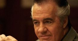 Paulie Walnuts, dressed sharply in a suit, smirks confidently at a dinner table, embodying mobster charm and style.