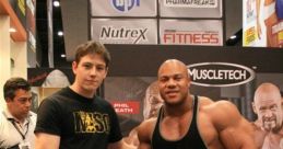 Phil Heath poses with a fan at a fitness expo, showcasing muscular physiques and brands like Muscletech in the background.