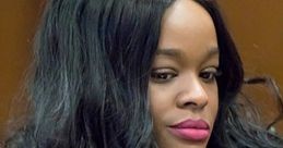 Close-up of a woman with long, wavy hair and vibrant lipstick, exuding confidence in a courtroom setting.