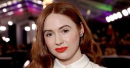 Karen Gillan showcases elegant fashion with red lips at a glamorous event, featuring soft waves and a chic white outfit.