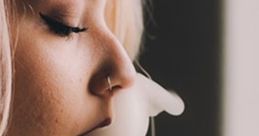 Woman with pink hair exhaling smoke while holding a smoking device, capturing a relaxed vibe and artistic expression.