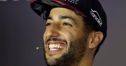 Daniel Ricciardo smiling during a press event, wearing Red Bull Racing team gear, showcasing his charismatic personality.