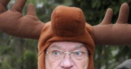 Man wearing a humorous moose hat in a forest, showcasing a quirky side of Swedish outdoor apparel.