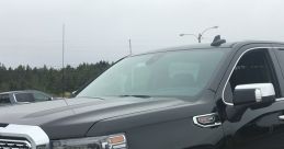 GMC Sierra Denali in black with chrome accents, showcasing a powerful design and luxury features on a gravel surface.