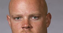 Headshot of a professional man in a suit with a red tie, featuring a bald head and piercing green eyes, exuding confidence.