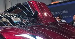 Sleek red sports car on display with dynamic lines, showcasing cutting-edge design and technology at an auto show.