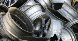 Piled metal car rims and wheels, showcasing various styles and conditions, ideal for recycling or restoration projects.