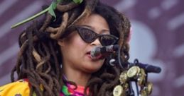 Colorful performer with dreadlocks playing guitar at a vibrant music festival, capturing the spirit of live entertainment.