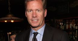 Chris Hansen in a formal suit at a social event, showcasing his signature style and charismatic presence.